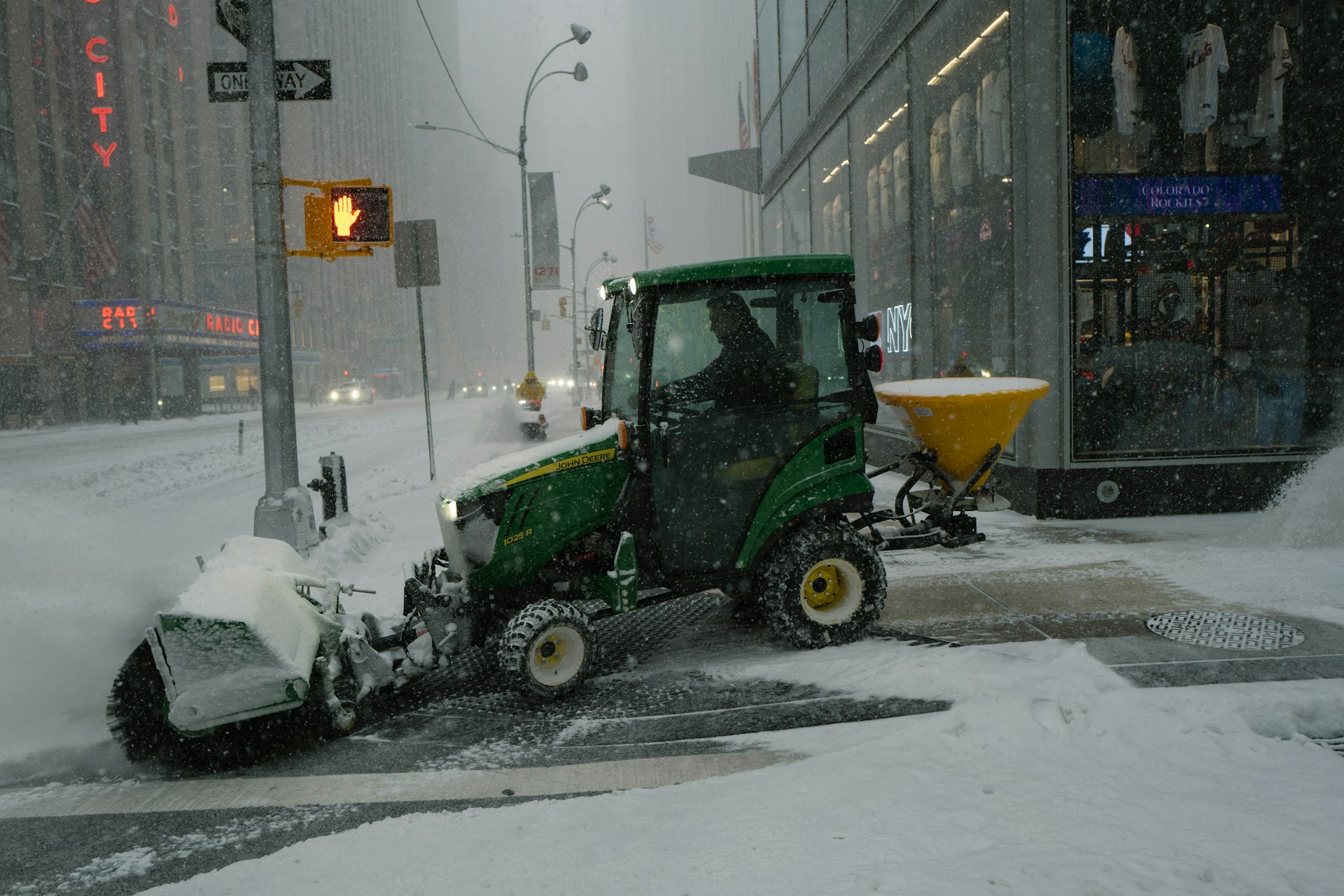 Compact tractor with snow-clearing attachment working through a heavy winter storm